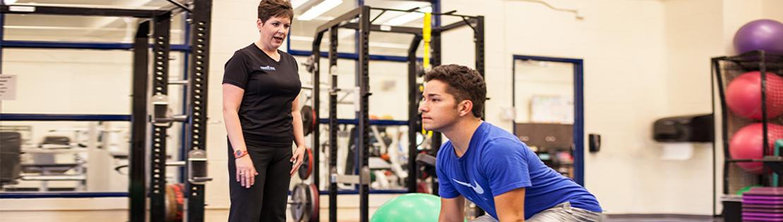 A trainer assists a man with a light fitness workout